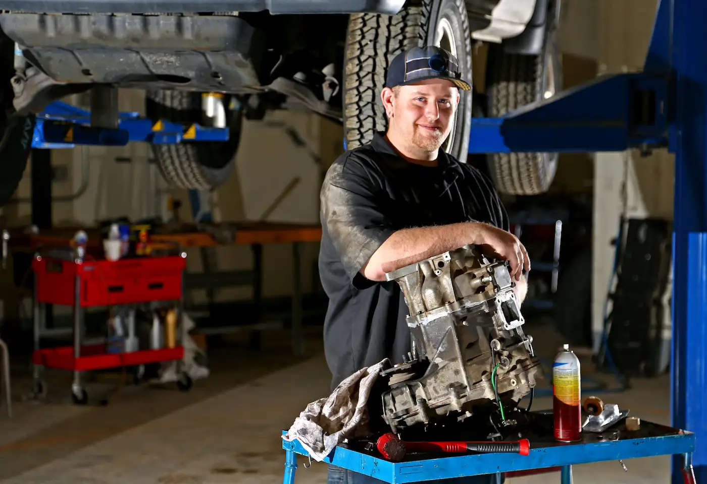 Smiling student in front of a car on a lift