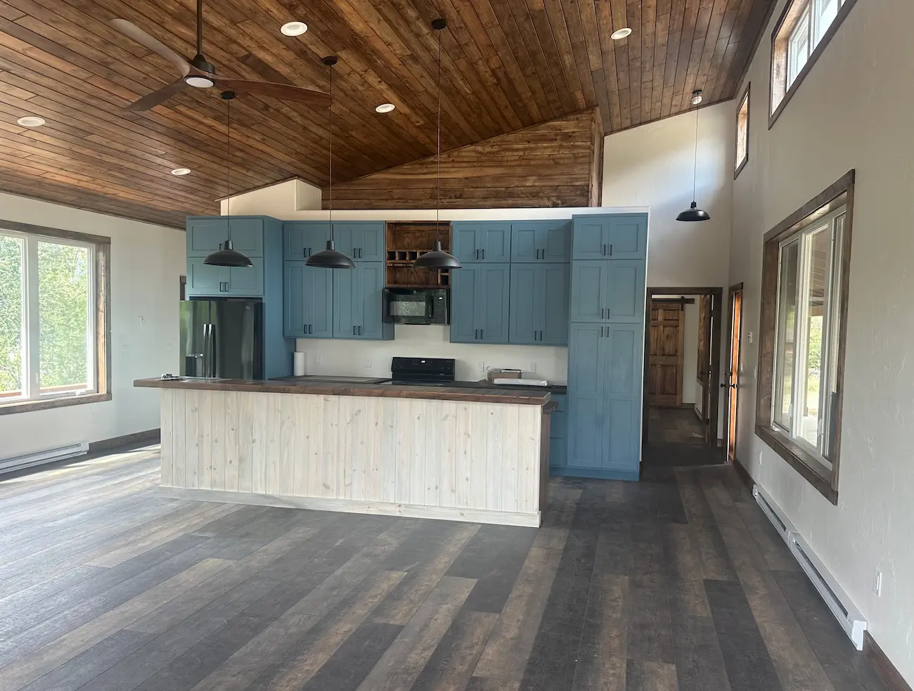 Interior view of the student-built COPERR home at 1024 East First Street, featuring custom blue cabinetry, a wood-plank ceiling, and kitchen island